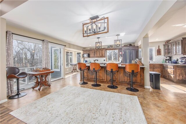 kitchen featuring tasteful backsplash, glass insert cabinets, light countertops, a large island, and stainless steel appliances