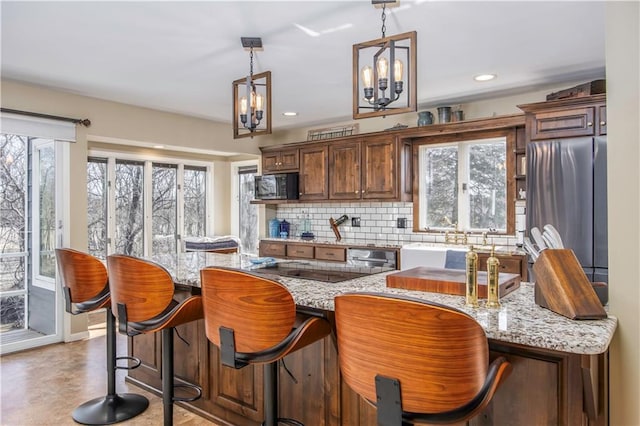 kitchen with freestanding refrigerator, plenty of natural light, light stone countertops, and backsplash