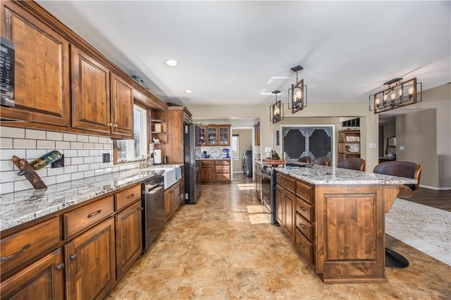 kitchen with decorative backsplash, a kitchen breakfast bar, light stone counters, and appliances with stainless steel finishes