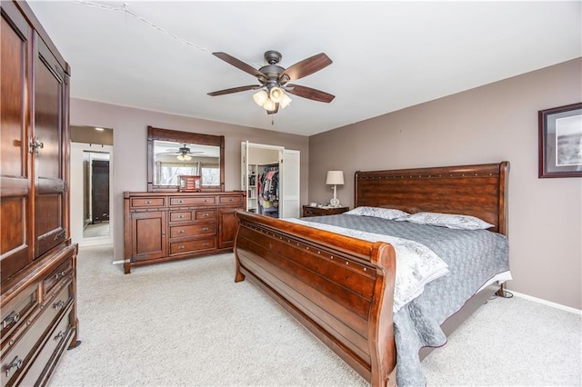 bedroom with baseboards, a walk in closet, light carpet, and a closet