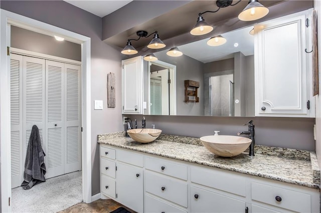 full bathroom with a closet, double vanity, and a sink