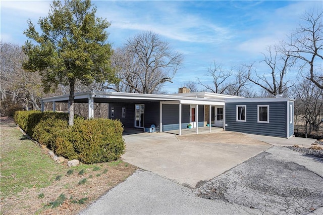 view of front of home featuring a carport, driveway, and a chimney