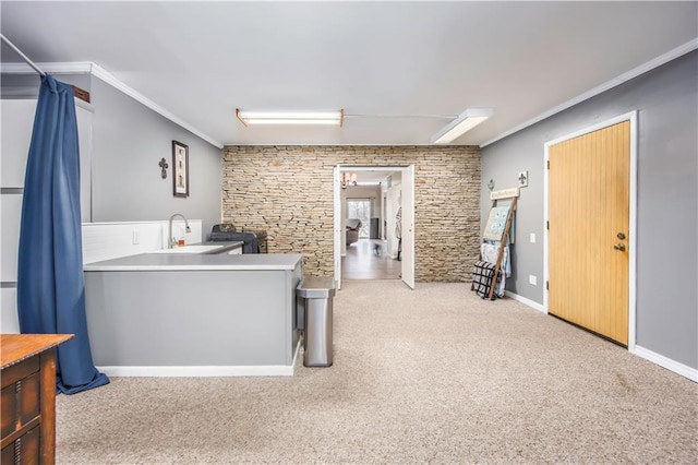 kitchen featuring a sink, crown molding, baseboards, and carpet floors