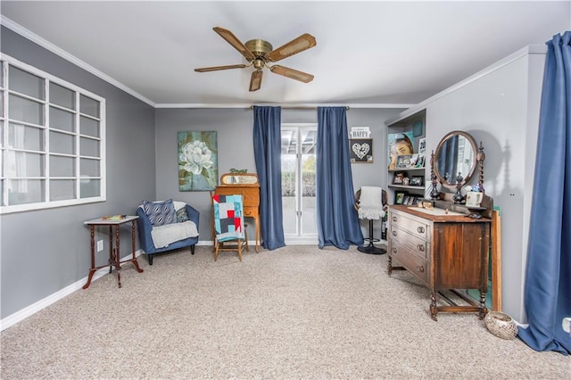 living area with baseboards, crown molding, carpet, and a ceiling fan