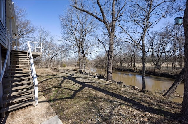 view of yard featuring stairway and a deck with water view