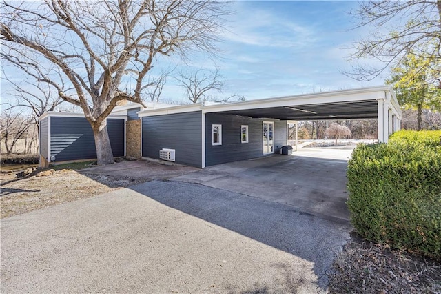 exterior space with an attached carport, aphalt driveway, and an outdoor structure