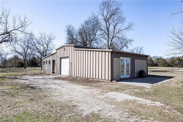 detached garage with french doors and dirt driveway