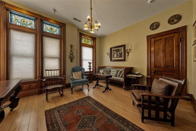 sitting room featuring light wood-style floors, visible vents, vaulted ceiling, and an inviting chandelier