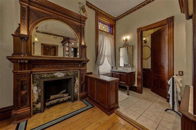 living area with light wood-type flooring, ornamental molding, and a fireplace