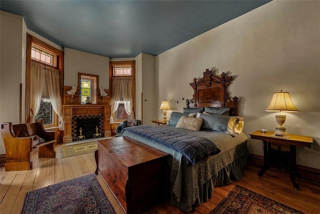 bedroom with a fireplace with raised hearth and hardwood / wood-style floors