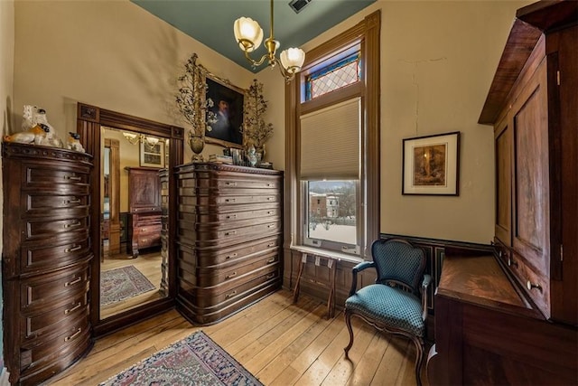 living area featuring a wainscoted wall, light wood-style flooring, and a chandelier