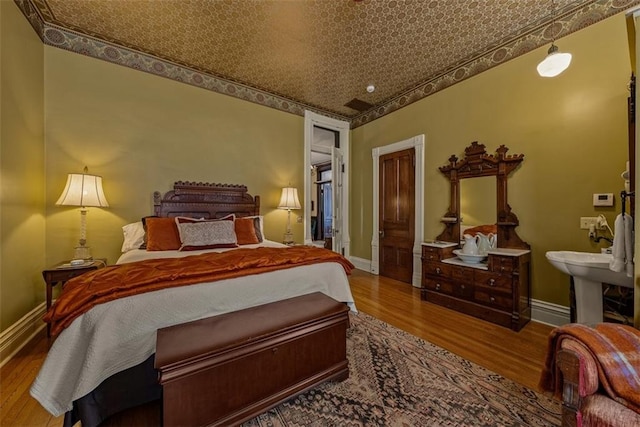 bedroom featuring an ornate ceiling, baseboards, and wood finished floors