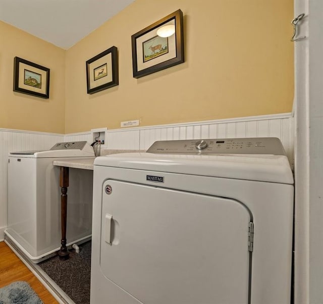 laundry area with a wainscoted wall, laundry area, wood finished floors, and washer and dryer