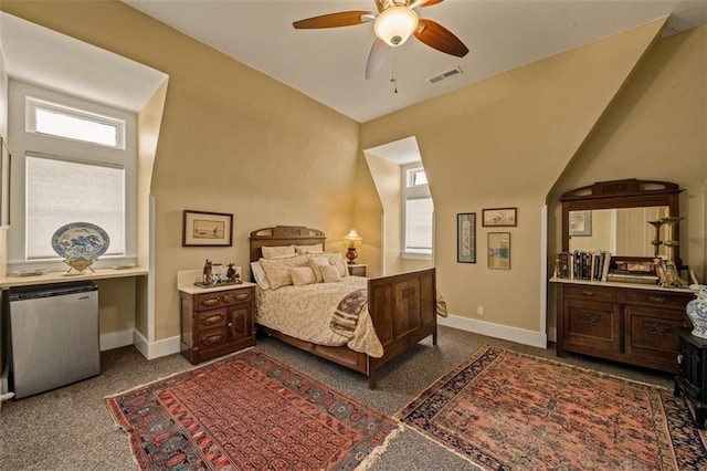 bedroom featuring baseboards, dark carpet, visible vents, and refrigerator