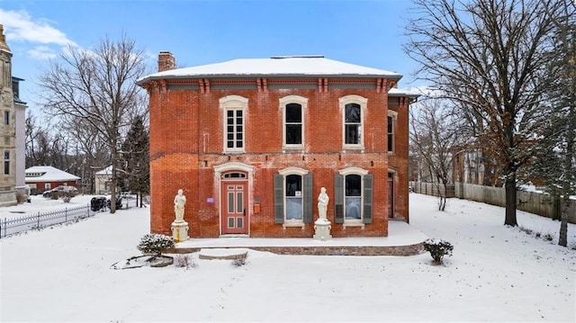 italianate house with brick siding, a chimney, and fence