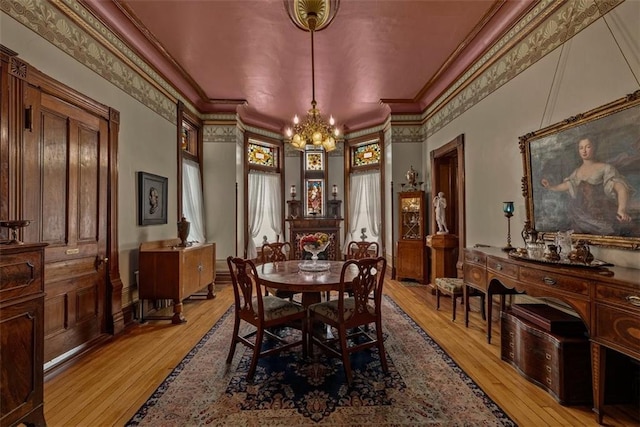 dining area with ornamental molding, a notable chandelier, and light wood-style flooring