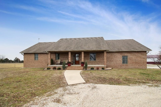 ranch-style home with brick siding, a front yard, and a shingled roof