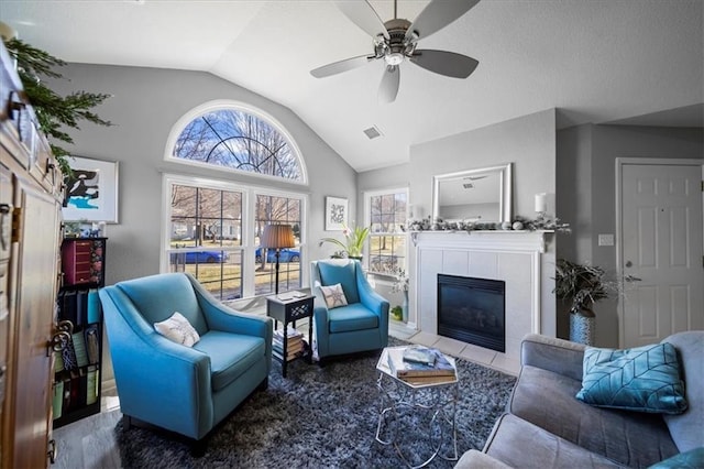 living room with lofted ceiling, ceiling fan, a fireplace, and visible vents