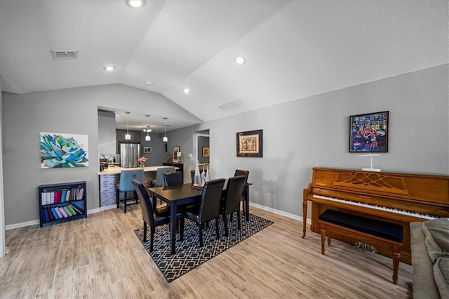 dining area with vaulted ceiling, light wood-type flooring, visible vents, and baseboards