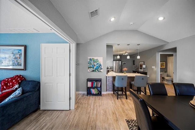 interior space with lofted ceiling, baseboards, visible vents, and light wood finished floors