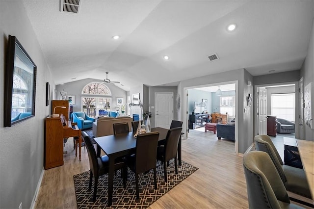 dining area featuring vaulted ceiling, light wood-style flooring, visible vents, and a ceiling fan