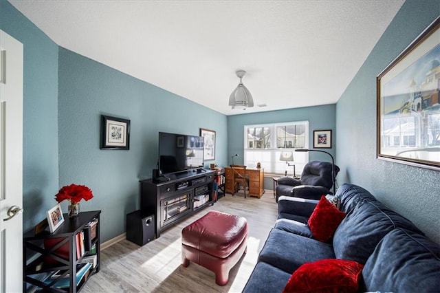 living room with a textured wall, wood finished floors, and baseboards