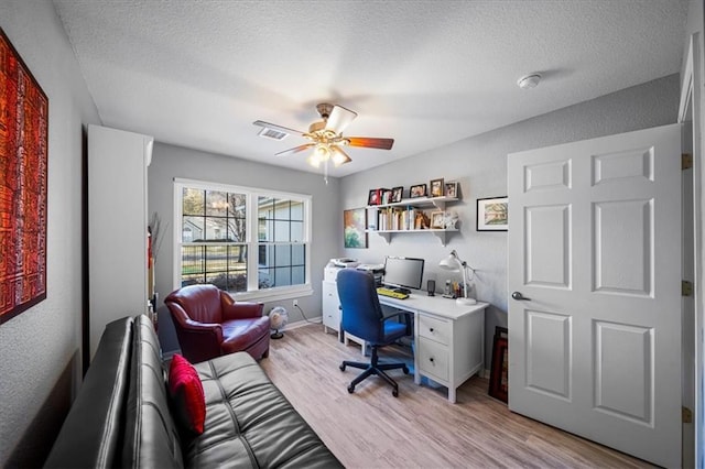 office space with light wood-type flooring, baseboards, visible vents, and a textured ceiling