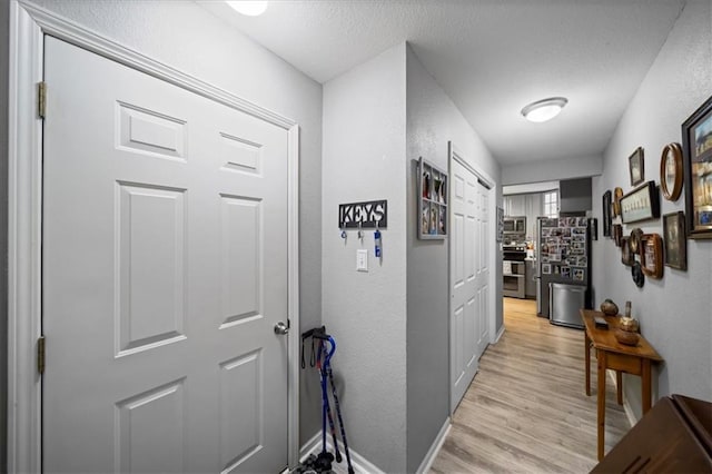 hall with light wood-style flooring and baseboards