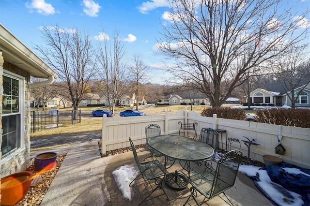 view of patio featuring a residential view, fence, and outdoor dining area