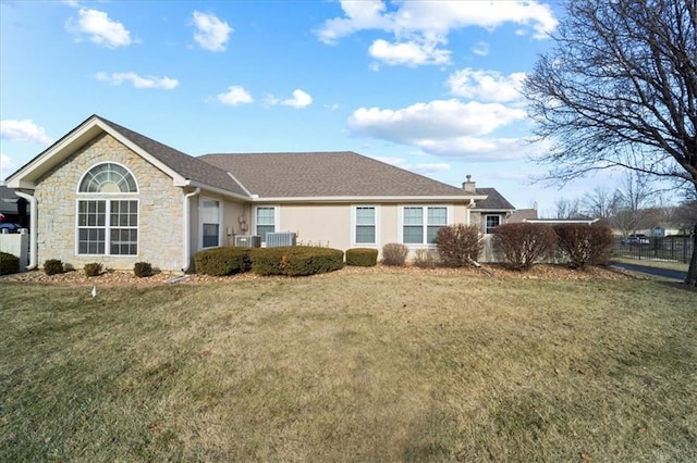 back of property with a chimney, stucco siding, a lawn, cooling unit, and stone siding