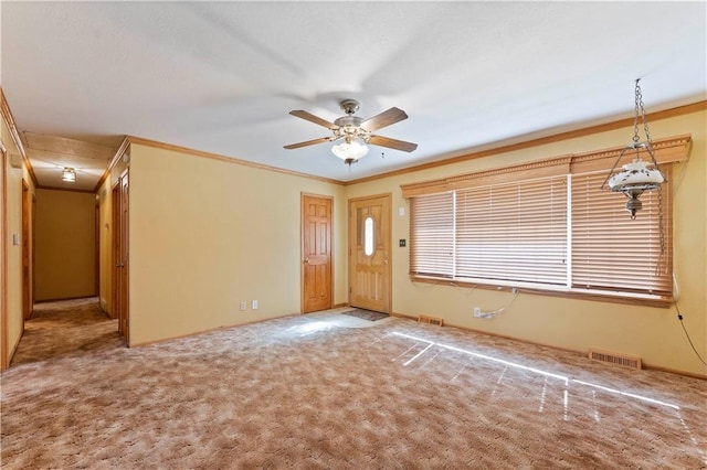 carpeted entryway featuring ceiling fan, visible vents, ornamental molding, and baseboards