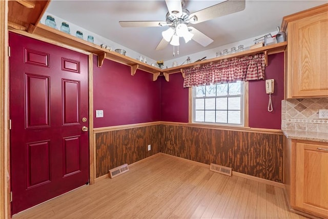 unfurnished dining area featuring a wainscoted wall, wood walls, and visible vents