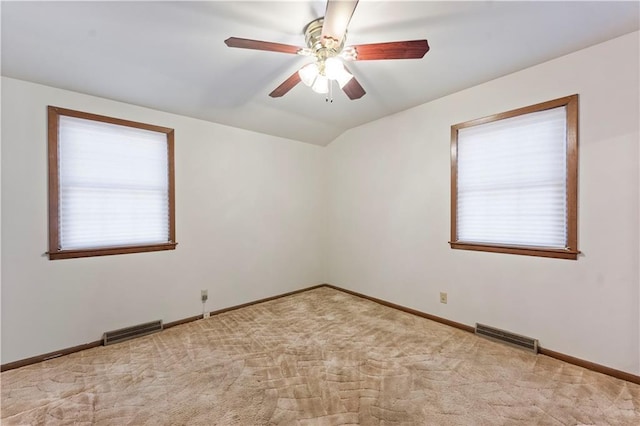 unfurnished room featuring carpet floors, lofted ceiling, visible vents, and plenty of natural light