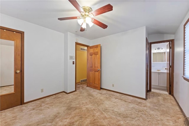 unfurnished bedroom featuring ensuite bath, light colored carpet, visible vents, and baseboards