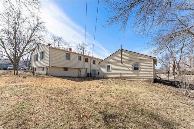 back of property with fence, a chimney, and a lawn