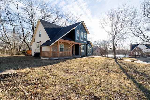 view of front of house featuring stone siding, fence, covered porch, and central AC