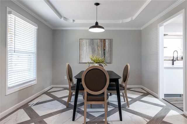 dining room featuring baseboards, a raised ceiling, and ornamental molding