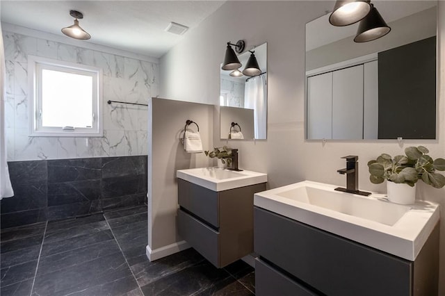 bathroom with marble finish floor, two vanities, visible vents, a sink, and walk in shower