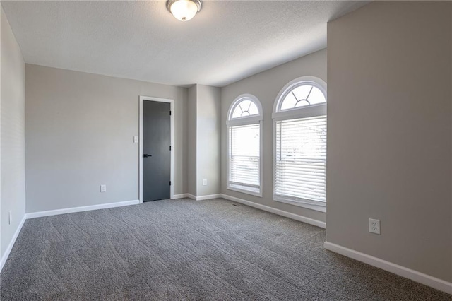 unfurnished room with carpet flooring, a textured ceiling, and baseboards