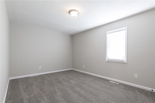 unfurnished room featuring a textured ceiling, carpet flooring, and baseboards