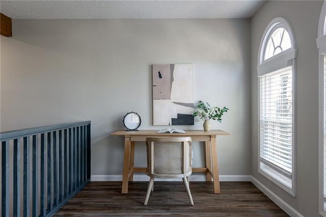 office space with dark wood-type flooring, a textured ceiling, and baseboards