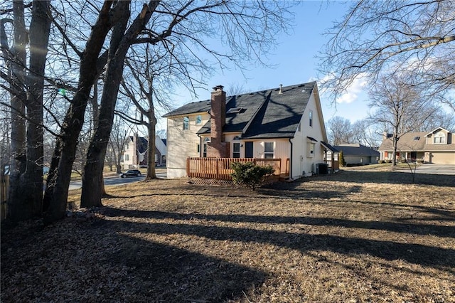 rear view of house featuring central AC, a chimney, a wooden deck, and a residential view