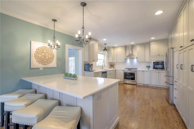 kitchen featuring a kitchen breakfast bar, dark wood-style floors, stainless steel appliances, wall chimney exhaust hood, and a sink