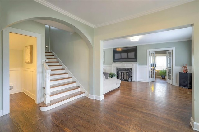 interior space with a fireplace, wood finished floors, wainscoting, and ornamental molding