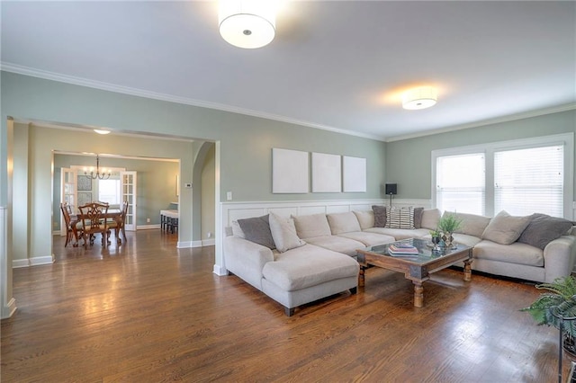 living area featuring a chandelier, baseboards, wood finished floors, and crown molding