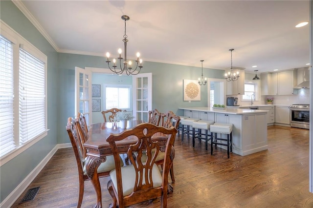 dining space with visible vents, a notable chandelier, dark wood finished floors, crown molding, and baseboards