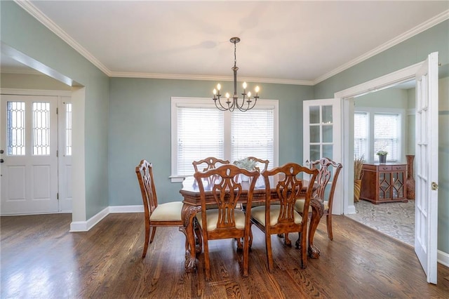 dining area with dark wood-type flooring, crown molding, baseboards, and a chandelier