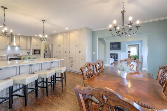 dining area with dark wood finished floors, a chandelier, a fireplace, and ornamental molding