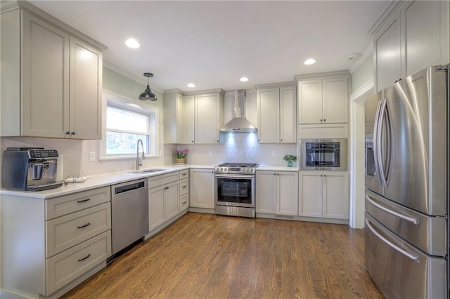 kitchen with wall chimney range hood, light countertops, appliances with stainless steel finishes, dark wood-style floors, and a sink