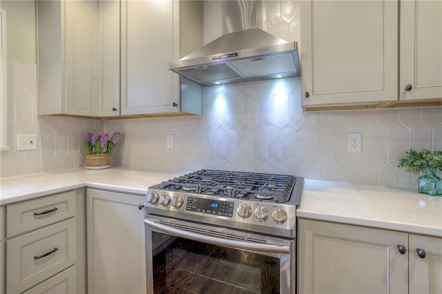 kitchen featuring gas range, wall chimney exhaust hood, light countertops, and backsplash